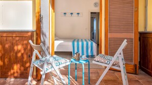 A room with a bed, a small table with a kettle, and two chairs. - Holiday Home 'Sky View' with Sea View, Shared Pool and Air Conditioning (Paduledda)