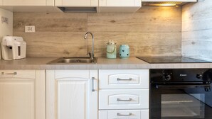 A kitchen with white cabinets, a stainless steel sink, a built-in oven, and a coffee maker. - Holiday Home 'Sky View' with Sea View, Shared Pool and Air Conditioning (Paduledda)