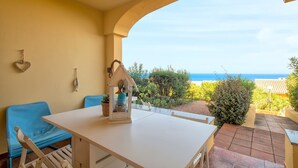 A patio with a white table and blue chairs, a decorative lantern, and a view of the sea. - Holiday Home 'Sky View' with Sea View, Shared Pool and Air Conditioning (Paduledda)