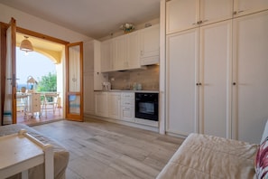 A kitchen with white cabinets, a built-in oven, and a dining area with a table and chairs.