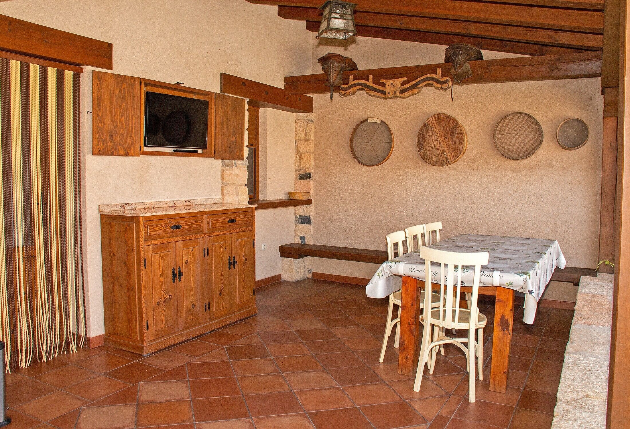 Una cocina con armarios de madera, una mesa de comedor con sillas y una pared decorada con platos.