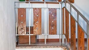 Een meerlaags interieur met een houten trap, een klein tafeltje en een deur naar een andere kamer.