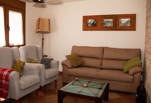 En stue med sofa, lænestole, sofabord og lampe.