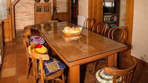Een eetkamer met een houten tafel, stoelen en een buffet met brood.