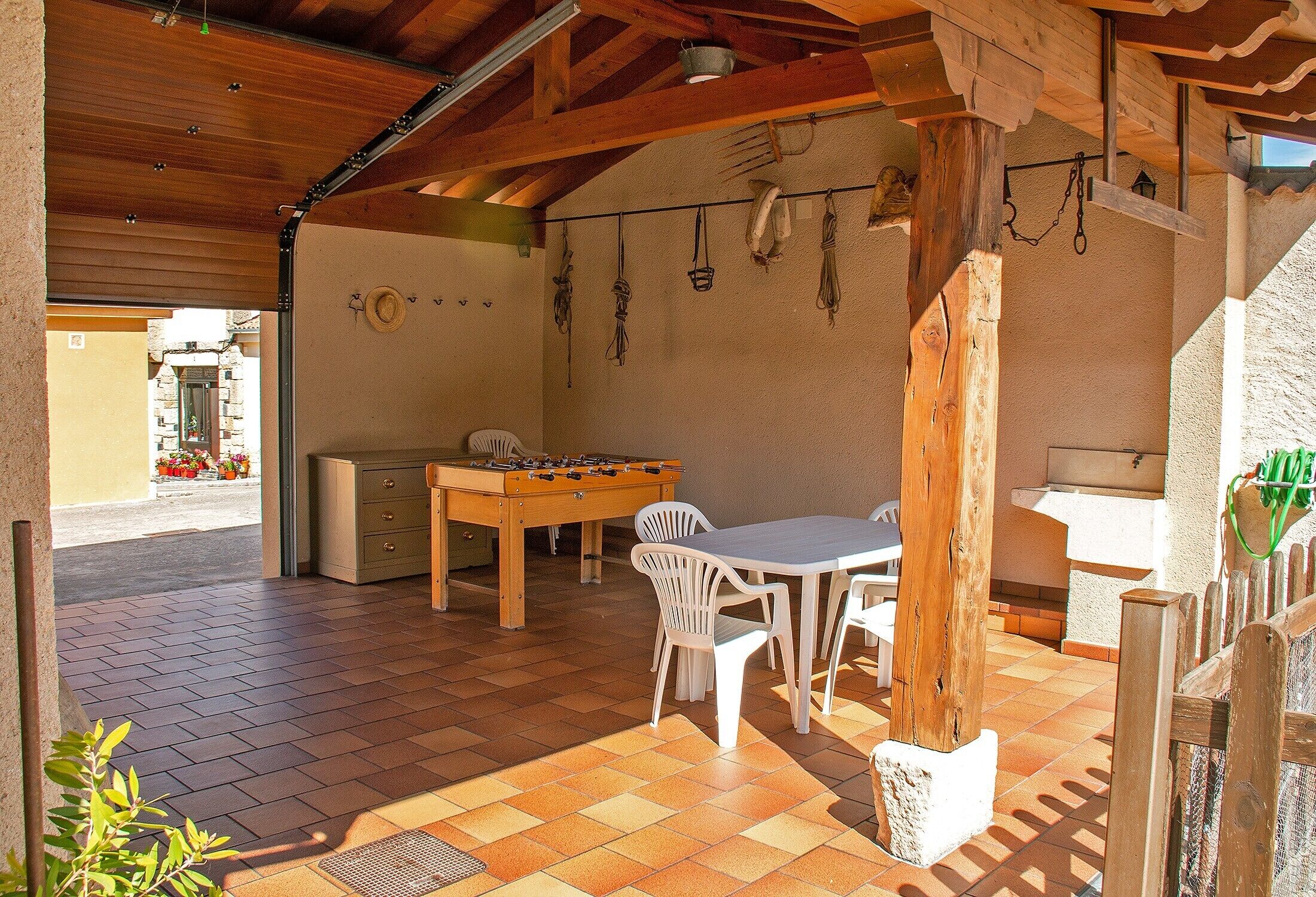 An outdoor patio with a wooden table and chairs, a foosball table, and a rustic wooden ceiling.