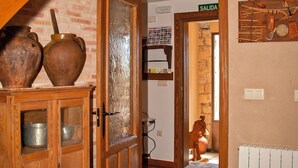 Een rustiek interieur met houten balken, een betegelde vloer en een deur naar een ruimte met de tekst 'SALIDA'.