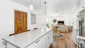 Una cocina moderna con una isla grande, armarios blancos e iluminación colgante.