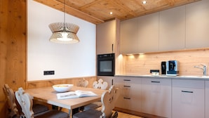A modern kitchen with wooden cabinetry, a built-in oven, and a coffee machine.