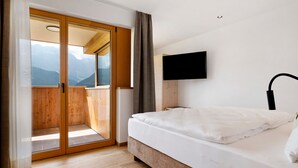 Une chambre avec un lit, une télévision et une vue sur les montagnes, visible à travers une porte coulissante.