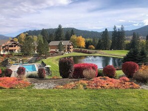 A resort with a swimming pool, a pond, and a well-maintained lawn.