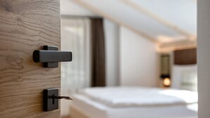 A modern bedroom with a wooden door, a bed, and a nightstand. - Apartment 'Fën' with Mountain View, Shared Garden and Wi-Fi (Wolkenstein)