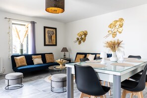 Un salon moderne comprenant un canapé, une table à manger, des chaises et des objets de décoration.