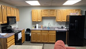 A kitchen with wooden cabinets, a black refrigerator, a microwave, and a sink. - Cozy 2-bedroom apartment in tranquil Nutter Fort with AC, WiFi. Close to I 79. (Clarksburg)