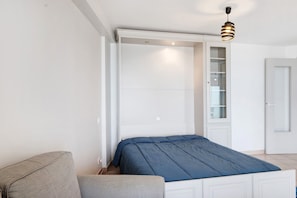 Quarto com cama, armário embutido, luminária pendente e porta.