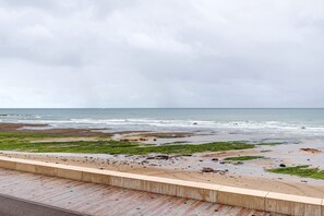 A beach view with a wooden deck and a stone wall. - Studio Apartment 'Le First  Vue Mer' with Sea View (Les Sables-d'Olonne)