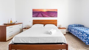 A bedroom with a bed, a nightstand, a dresser, a painting, and a blue bedspread. - Holiday Home 'Il Rifugio Di Franz' with Air Conditioning (Vernole)