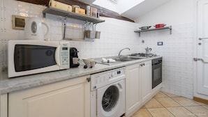 A compact kitchen with a microwave, coffee maker, sink, and a washing machine. - Heart of Florence: Central, Cozy Apt with Elevator (Firenze)