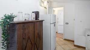 A kitchen with a wooden cabinet, a white refrigerator, and a tiled floor. - Heart of Florence: Central, Cozy Apt with Elevator (Firenze)