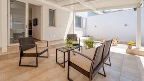 An outdoor patio with wicker furniture, a glass door leading to a balcony, and potted plants.