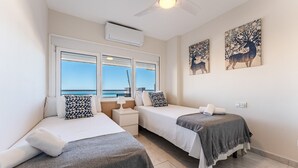 A hotel room with two beds, a window with a view of the sea, and two wall-mounted paintings. - MalagaSuite Seaview Babilonia (Torremolinos)