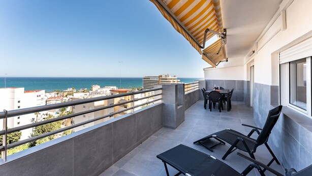 A balcony with a view of the sea, a table with chairs, and a window. - MalagaSuite Seaview Babilonia (Torremolinos)