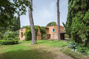 Una casa a due piani con un prato curato, circondata da alberi e arbusti.