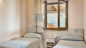 Una habitación con dos camas, una ventana con vistas, una mesita de noche y una cortina.