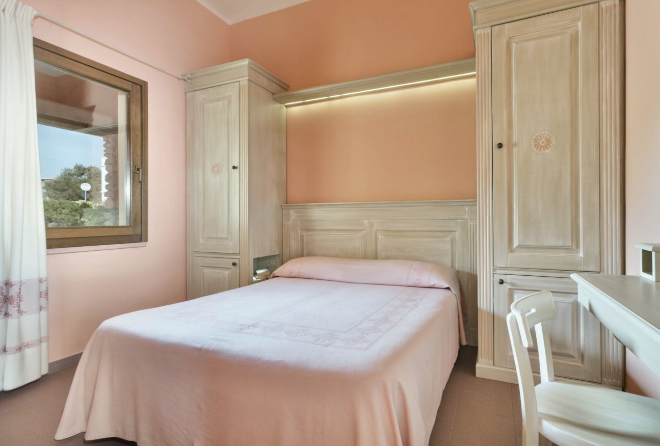 A bedroom with a bed, a desk, and a wardrobe.