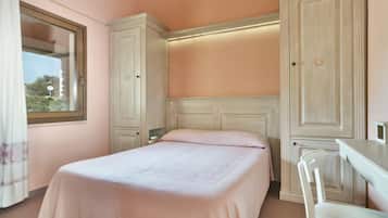 A bedroom with a bed, a desk, and a wardrobe.