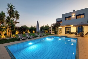 A swimming pool with lounge chairs and a modern building with a blue door. - Villa Mariani II (Rhodes)