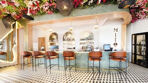 A bar area with a checkered floor, bar stools, and a counter with a name sign. - Botanico Hotel y Spa (Caucasia)