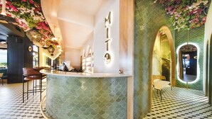A bar area with a green, fish-scale patterned counter, a wooden chair, and a wall with a 'Mito' sign. - Botanico Hotel y Spa (Caucasia)