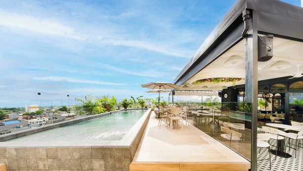 A rooftop pool area with a view of the city, outdoor seating, and a covered bar area. - Botanico Hotel y Spa (Caucasia)