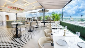 A rooftop restaurant with outdoor seating, a patterned floor, and a view of the city. - Botanico Hotel y Spa (Caucasia)