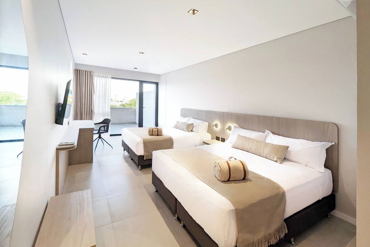 A modern hotel room with a large bed, a desk, and a chair.