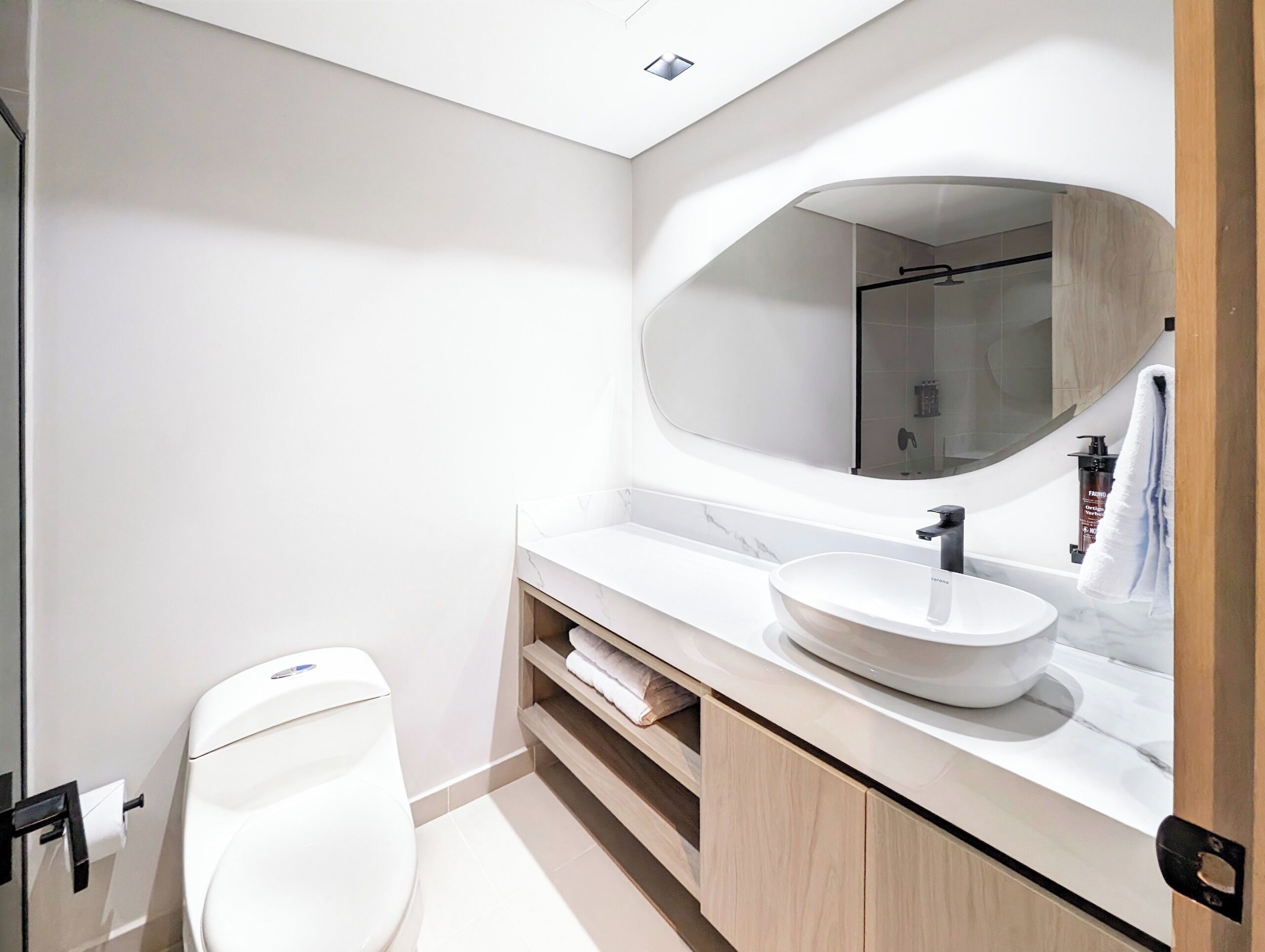 A modern bathroom with a white toilet, a large mirror, and a white sink.