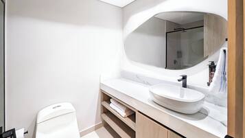 A modern bathroom with a white toilet, a large mirror, and a white sink.