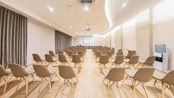 A conference room with rows of chairs, a projector screen, and a water dispenser.