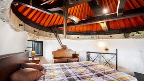 Una habitación con una cama de madera, un cabecero, un banco de madera y una barandilla de metal.