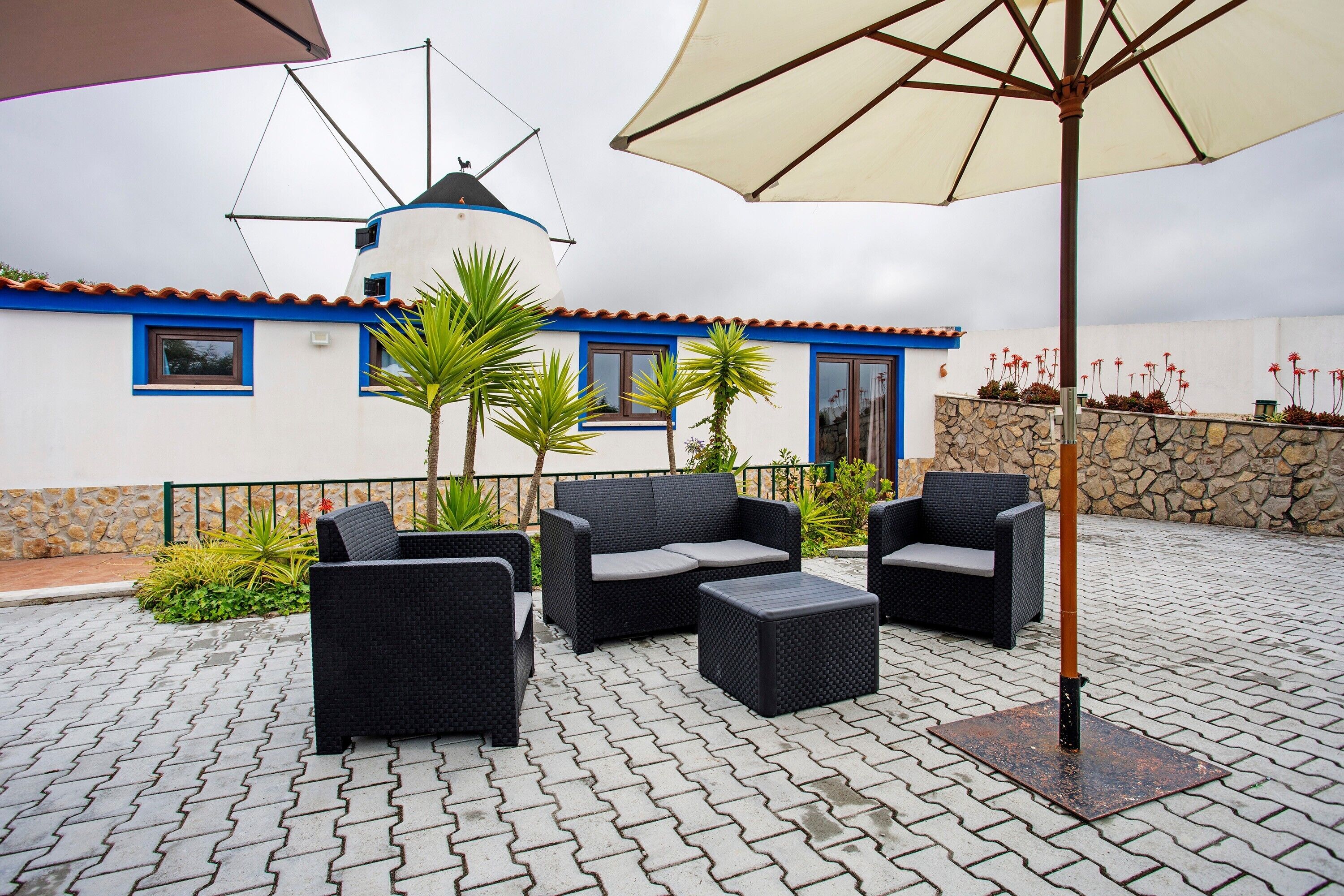 An outdoor patio with wicker furniture, a windmill, and a stone wall.