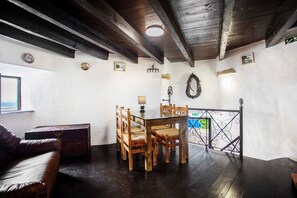 Ein Zimmer mit einem Holzesstisch, Stühlen, einer Couch und einer kleinen Schmucktruhe.