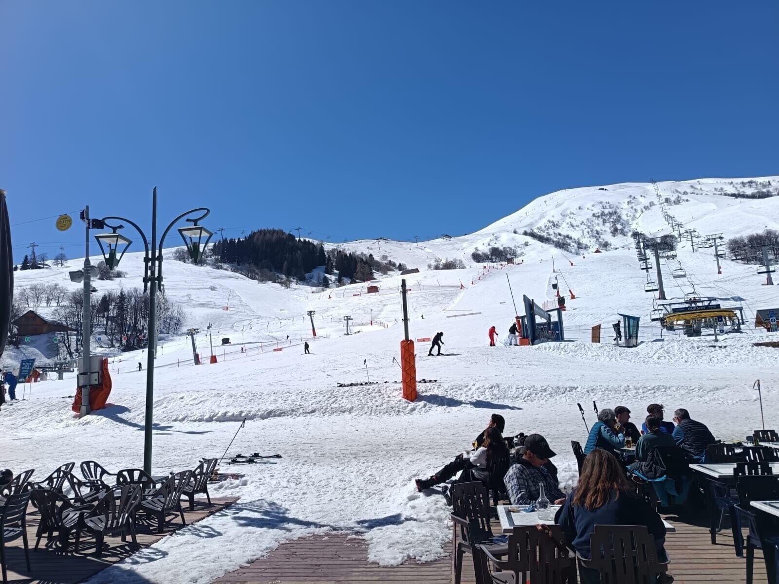 Een besneeuwde buitenruimte met een houten terras, stoelen en tafels, vermoedelijk een ruimte om te eten of te ontspannen.