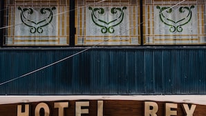 Ein Hotel Eingang mit einem Schild mit der Aufschrift 'HOTEL REX' und dekorativen Glasfenstern darüber.