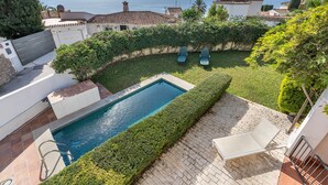 Une piscine avec vue sur la mer, une terrasse avec des chaises et un jardin bien entretenu.