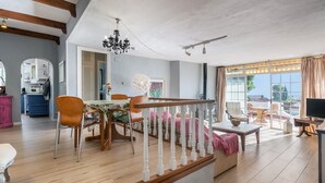 Un vaste espace de vie comprenant un escalier, une table à manger, des chaises et un téléviseur.
