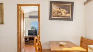 Un comedor con una mesa de madera, sillas, un cuenco, un cuadro y un televisor al fondo.
