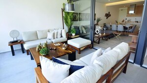 A modern living room with a sofa, coffee table, and a dining area with chairs and a table. - Beachfront condo in the heart of Nuevo Vallarta (Nuevo Vallarta)