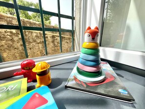 A window with a view of a construction site, a colorful toy structure, and a laptop with a Disney sticker. - Happy Family Apartments Maggiolino (Genoa)