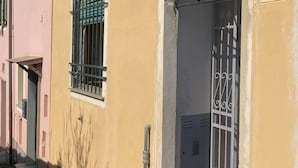 Un immeuble à la façade jaune, avec une porte numérotée et une fenêtre orn ée de barreaux en métal.