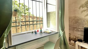 Un bureau spacieux avec une grande fenêtre, des rideaux verts, un bureau équipé d’un ordinateur et de livres.